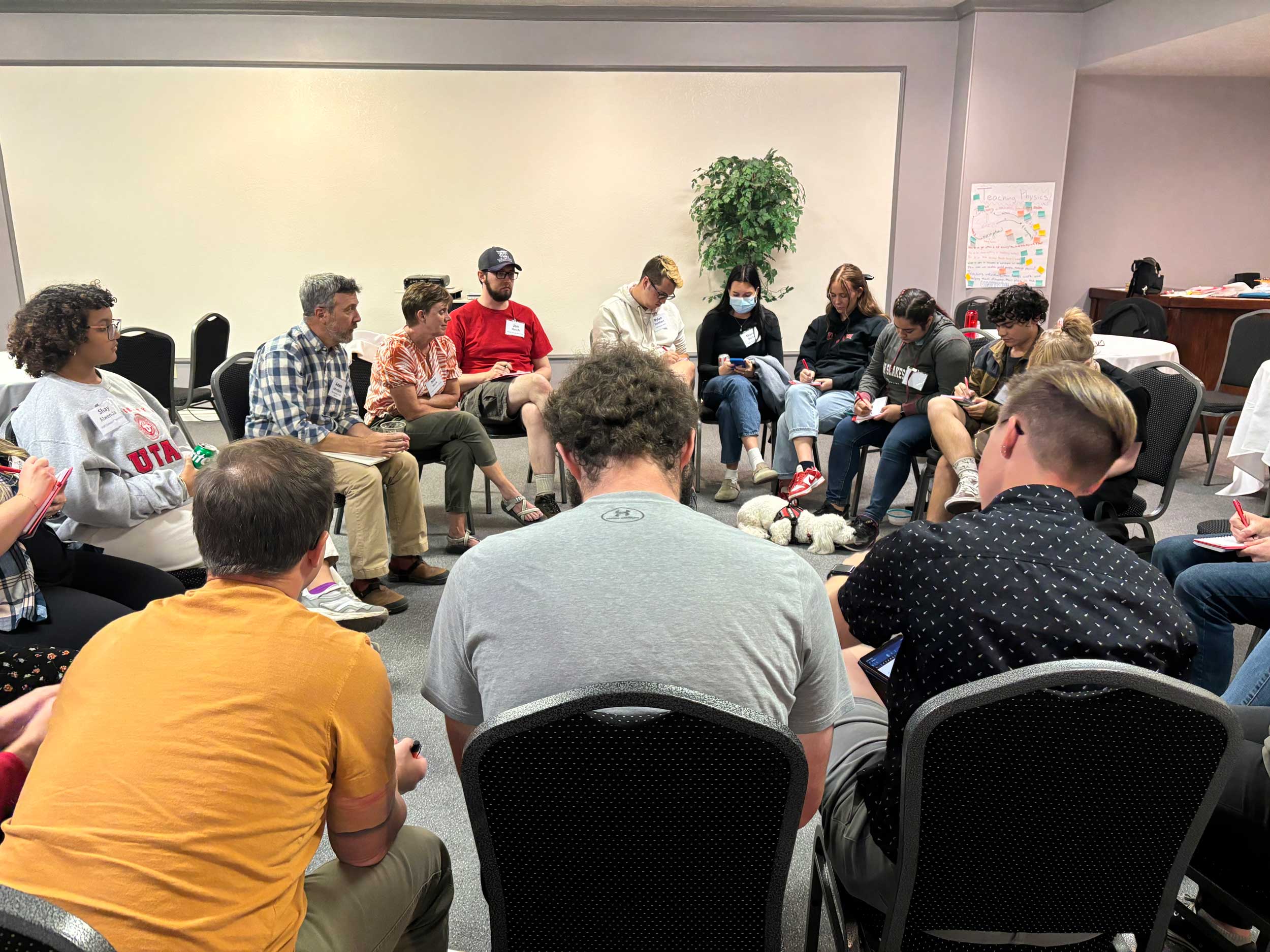 A group of people sit together in a circle of chairs