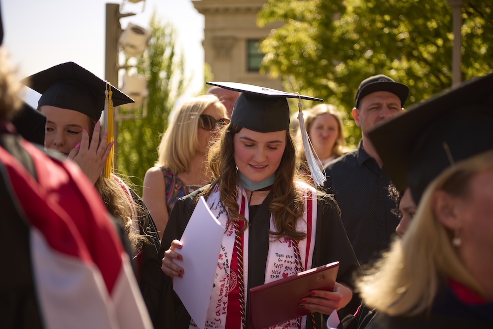 education student at graduation looking down at her diploma