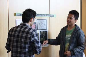 two males chatting in front of poster