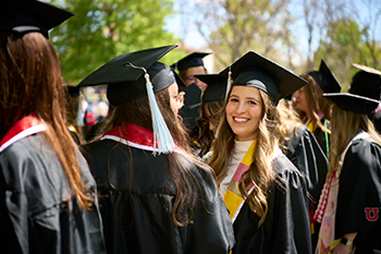 female graduate smiling amongst other student graduates