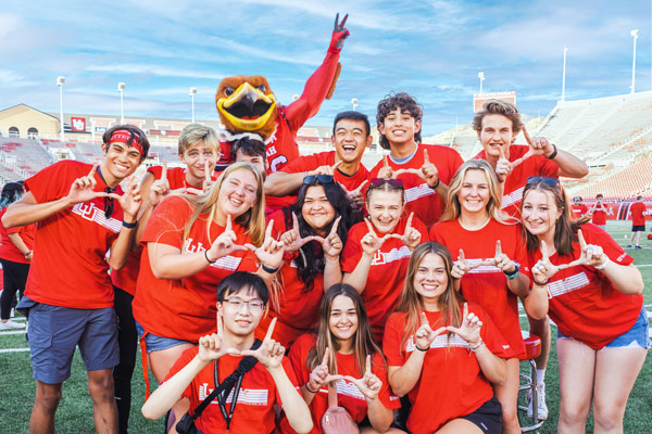 a group of students wearing U of U shirts, flashing the U handsign, with the swoop mascot