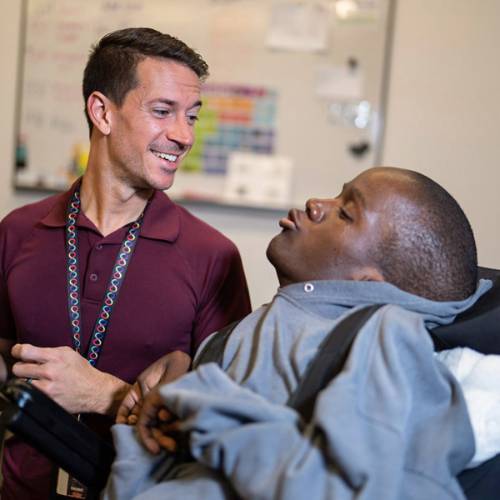 severely disabled student of color in a wheelchair communicating with instructor