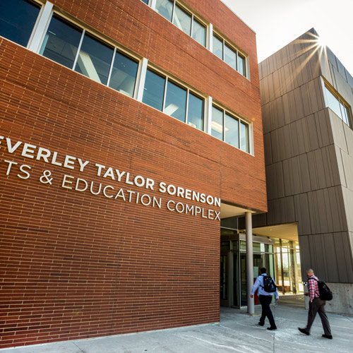 a close view of the Sorenson Arts & Education complex with two people of color to the doors.