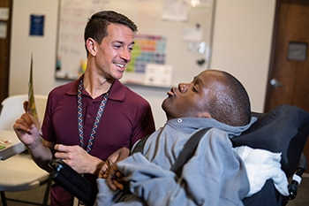 instructor displaying something to a student who is in a wheelchair