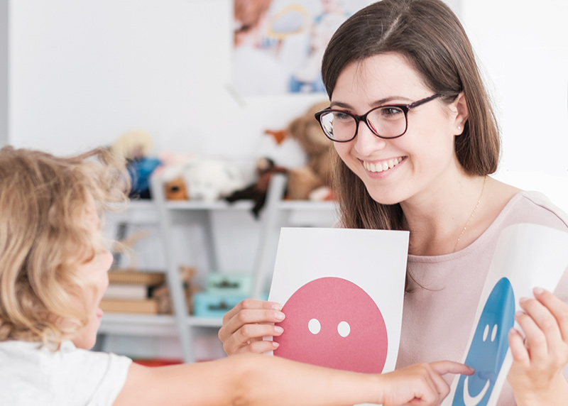 Educator showing a young child smiley faces